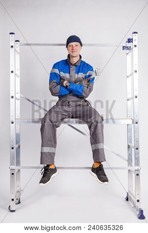 The Builder, The Installer Sits At A Height With A Tool In His Hands.