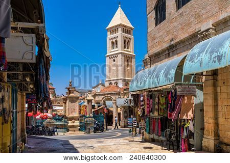 JERUSALEM, ISRAEL - JULY 16, 2017: Small square with fountain among gift shops as belfry on background in Muristan - famous historic complex of streets in Christian Quarter of Old City of Jerusalem.
