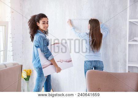 I Love Art. Beautiful Curly-haired Girl Posing For The Camera And Holding A Picture While Her Roomma