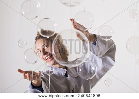 A Mad Scientist Is Experimenting With Glass Balls. A Woman In A White Robe Smiles Strangely And Stre