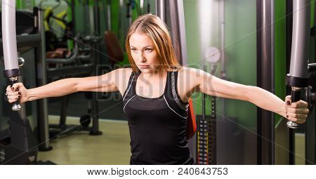 Woman Doing Fitness Training On A Butterfly Machine With Weights In A Gym.
