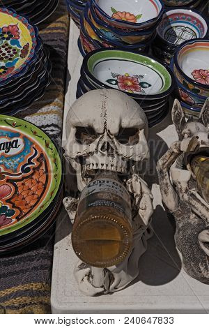 Mahahual, Mexico-march 06, 2018:  Beer Drinking Skull Between Colored Ceramic Bowls At A Stall In Ma