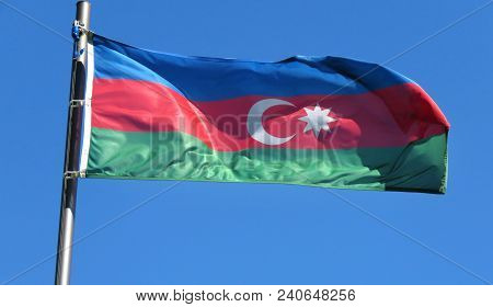 National Flag Of Azerbaijan On A Flagpole In Front Of Blue Sky.