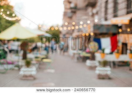 Blurred Background With Group Of Peolple Sitting At The Cafe Veranda Outside.