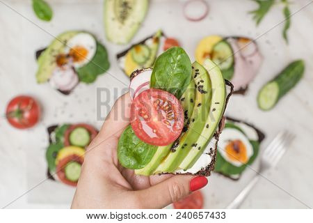One Sandwich With Fresh Summer Tomato And Avocado In Female Hand. Close Up.