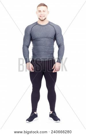 Portrait Of Handsome Well-muscled Gym Instructor In Sports Tights And Rashguard Posing On White Back