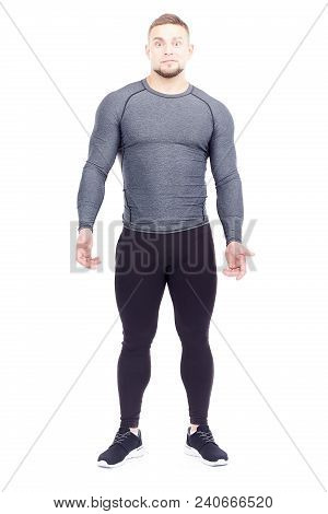 Portrait Of Handsome Well-muscled Gym Instructor In Sports Tights And Rashguard Posing On White Back