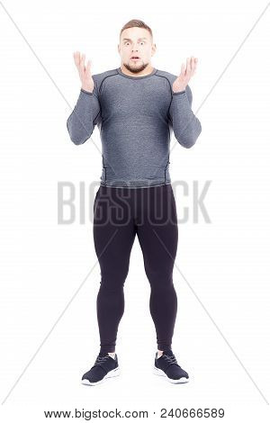 Portrait Of Handsome Well-muscled Gym Instructor In Sports Tights And Rashguard Posing On White Back