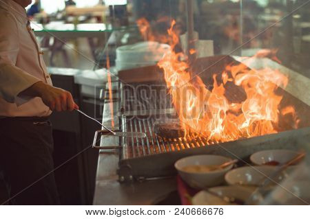 Master chef cooking delicious grilled meat steak with vegetables on a barbecue