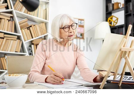 Self Education. Appealing Senior Woman Studying While Wearing Glasses