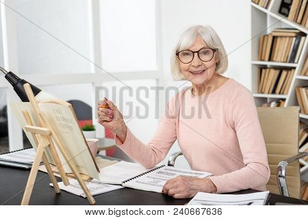 Educate Yourself. Merry Senior Woman Studying While Grinning To Camera