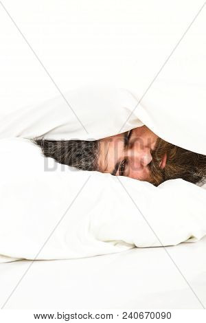 Man With Drowsy Face Lies On Pillow Under Blanket. Guy With Beard Hides Face Under Blanket. Rest And