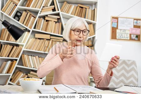 Educational Method. Meditative Senior Woman Using Tablet While Sipping Tea
