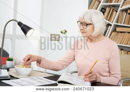 Healthy Snack. Appealing Mature Woman Consuming Snack While Writing