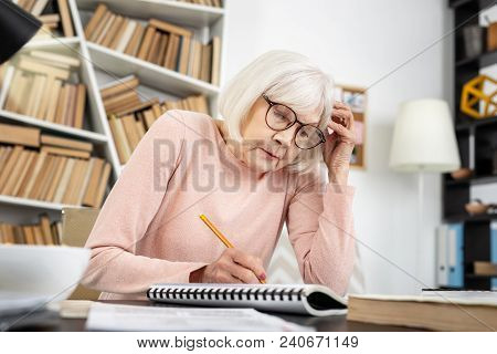 Too Difficult. Uneasy Mature Woman Touching Head While Writing