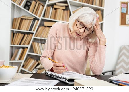 Complicated Task. Concentrated Mature Woman Rubbing Head While Doing Task