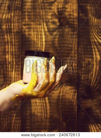 Female Hand Smeared In Golden Glister Holding Jar With Colorful Paint On Brown Vintage Studio Backgr
