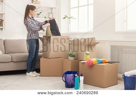 New Home Cleaning. Young Woman Tidying Up And Unpacking Boxes After Moving To New Apartment. Girl Wi