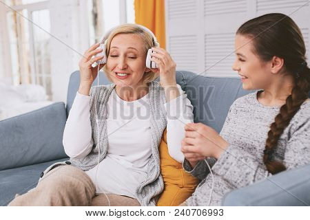 Generation Gap. Pleased Female Keeping Smile On Her Face While Listening Favorite Song