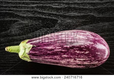 One Striped Purple Eggplant Top View Isolated On Black Wood Background