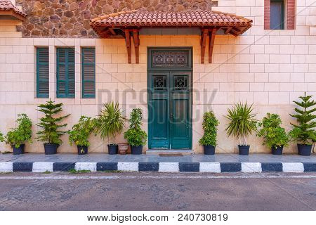 Facade Of The Clock Tower In Montaza Public Park With Green Wooden Door With Red Tile Canopy Above A