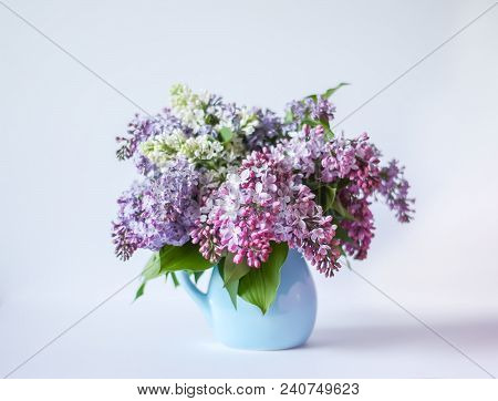Beautiful Bouquet Of Fragrant Purple Flowers In Blue Ceramics Vase On Light Background. Syringa Vulg