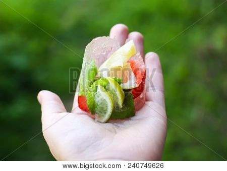 Melting Ice Cube With Strawberry, Lemon And Fresh Green Mint Leaves In A Hand