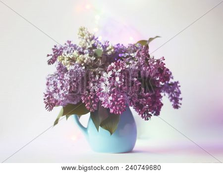 Beautiful Bouquet Of Fragrant Purple Flowers In Blue Ceramics Vase On Light Background. Syringa Vulg