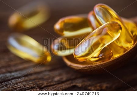 Close Up Vitamin D And Omega 3 Fish Oil Capsules Supplement On Wooden Plate For Good Brain , Heart A