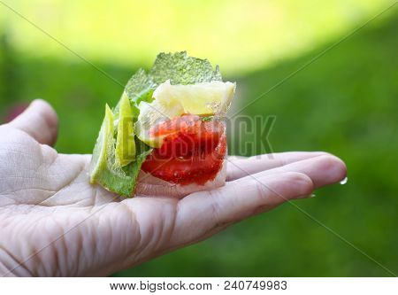 Melting Ice Cube With Strawberry, Lemon And Fresh Green Mint Leaves In A Hand