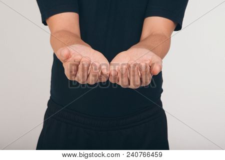 A Man In A Black T-shirt Holds His Hands In Front Of Him Palms Up