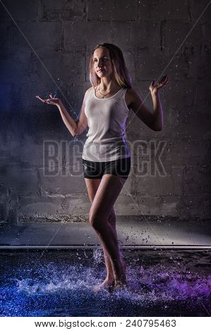Girl In The White Shirt With Water Drop In A Dark Room Illuminated By Light During A Photoshoot With