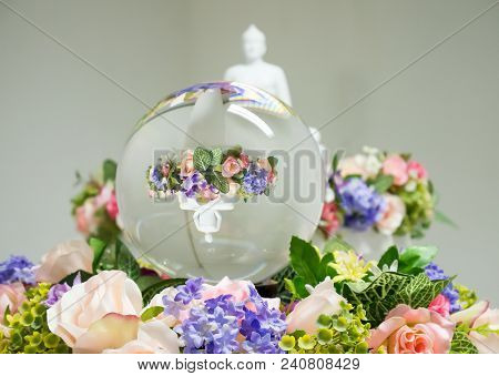 Mirrored Buddha In A Glass Ball On A Flower Bouquet