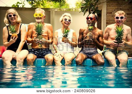 Cool seniors acting youtful by a swimming pool
