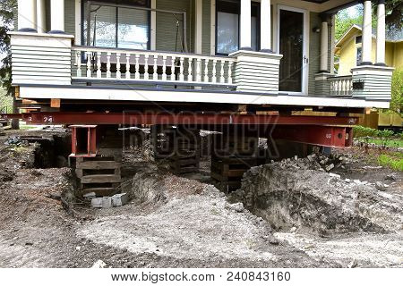 An Old House  (exposing The Porch) Rests On Steel Girders As A New Concrete Basement Is Being Create
