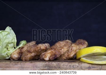 Breaded Chicken Meat With Salad And Lemon Resting On A Rustic Wooden Board