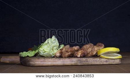 Breaded Chicken Meat With Salad And Lemon Resting On A Rustic Wooden Board