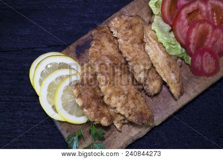 Breaded Chicken Meat With Salad And Lemon Resting On A Rustic Wooden Board