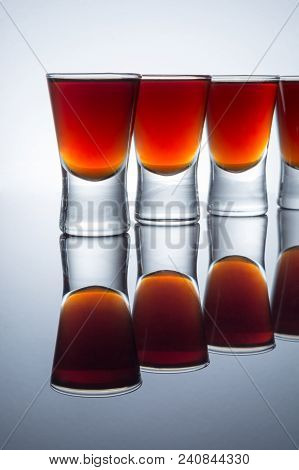 Small Glasses With A Drink Shots Of Alcohol Stainding In A Table With Reflection