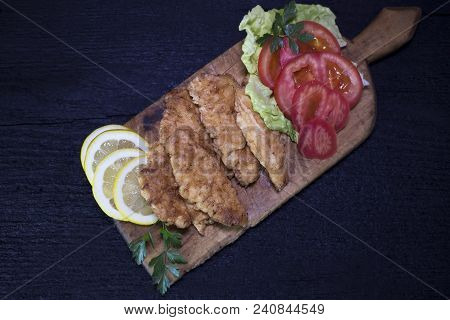 Breaded Chicken Meat With Salad And Lemon Resting On A Rustic Wooden Board