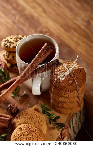 Christmas Concept With A Cup Of Hot Tea, A Large Set Of Cookies On A Homespun Napkin, Cinnamon Stick