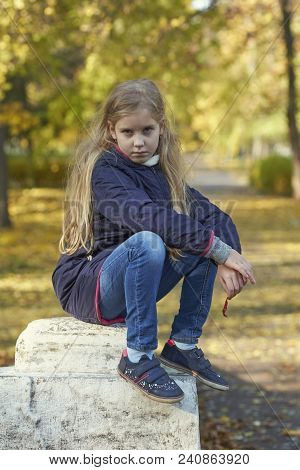 A Girl In Autumn Yellow Leaves In Sunset Rays