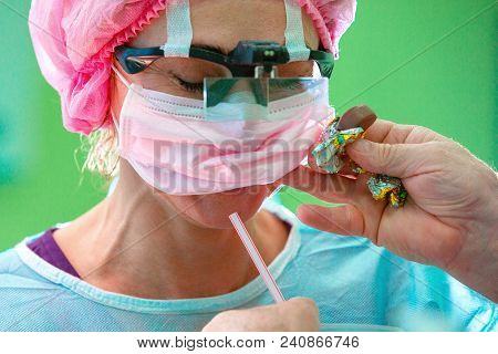Female Sergeon Wearing In Mask And Hat Takes A Break With Coffee During Long Operation.