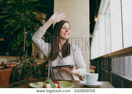 Woman Sitting In Coffee Shop At Table With Cup Of Cappuccino, Cake, Relaxing In Restaurant During Fr