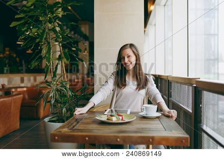 Woman Sitting Alone Near Big Window In Coffee Shop At Table With Cup Of Cappuccino, Cake, Relaxing I
