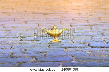 Bronze Aladdin Lamp On Cobbles. Fairy Tale Oriental Concept Of Fulfillment Of Desires.