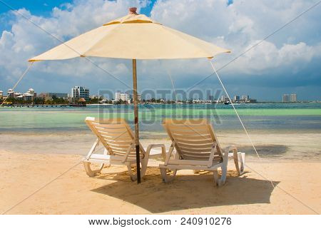 Sun Loungers And A White Umbrellas For Tourists On The Beach In Cancun. Mexico.