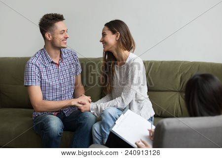 Happy Young Couple Smiling Reconciled After Quarrel, Holding Hands And Looking Into Eyes After Posit