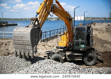 Big Excavator On New Construction Site. Excavator Loader Machine During Earthmoving Works Outdoors A
