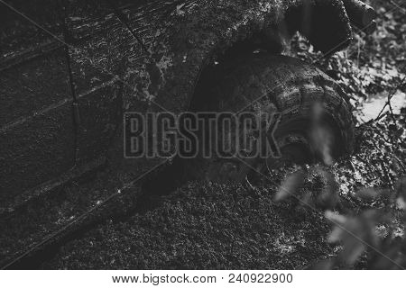 Offroad Tire Covered With Mud Overcomes Obstacles On Nature Background. Wheel In Deep Puddle Of Mud.